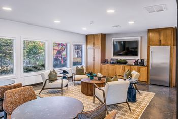 A modern living room with a television, a kitchen area, and a dining table.
